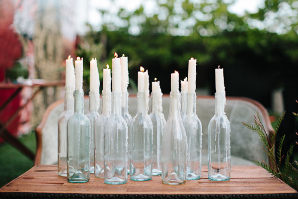 Multiple glass bottles with tall half melted candles in them